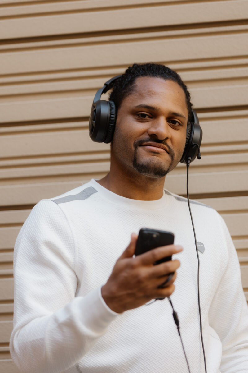 Benjamin Adjei trägt Kopfhörer und hält ein Smartphone in der Hand