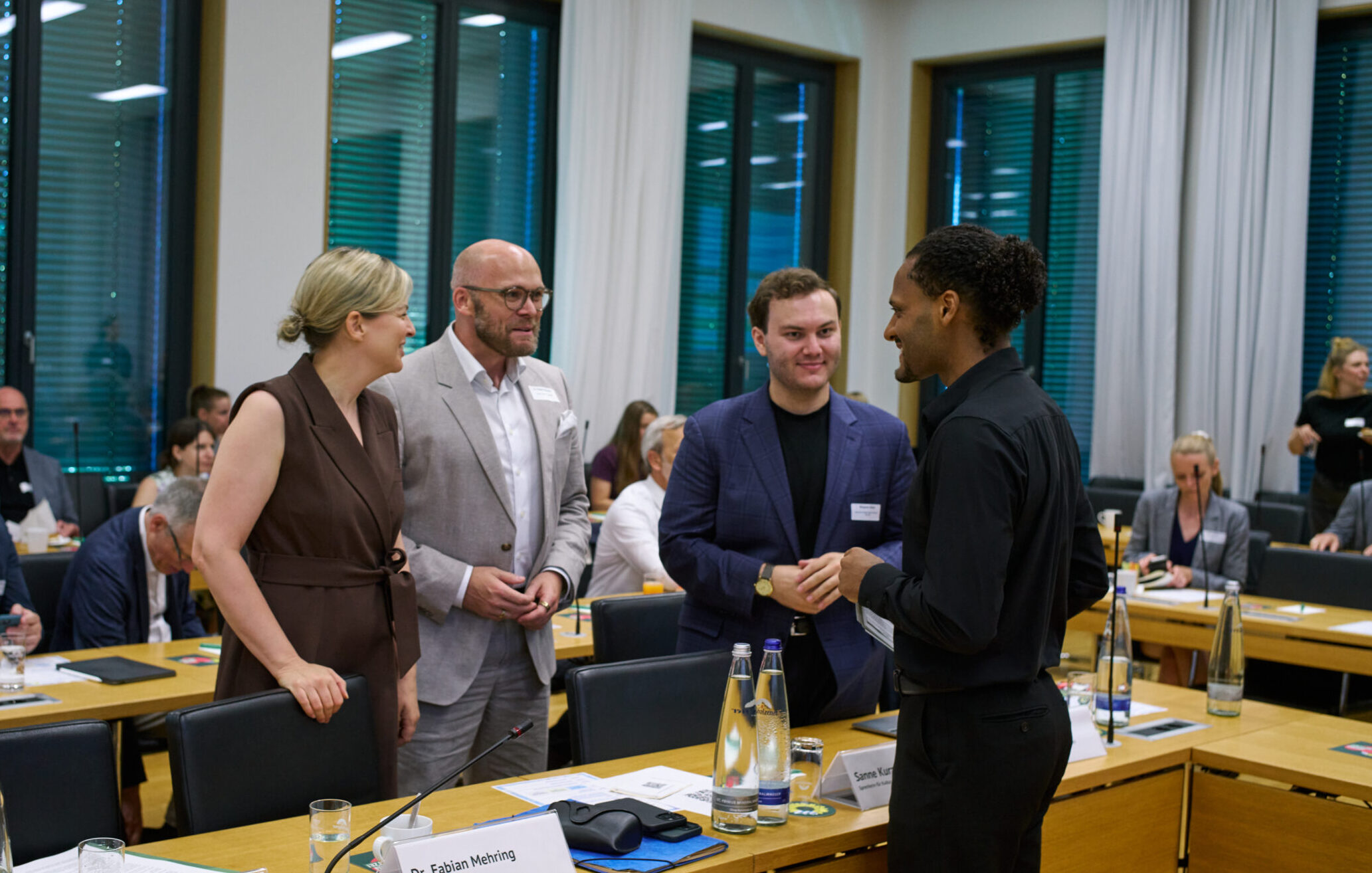 Katharina Schulze, Dr. Fabian Mehring, Benjamin Shultz und Benjamin Adjei unterhalten sich in einem Konferenzsaal.